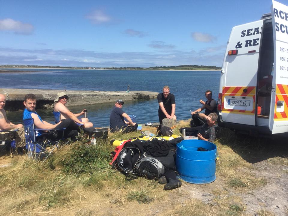 Club members resting beside the shoreline during a trip