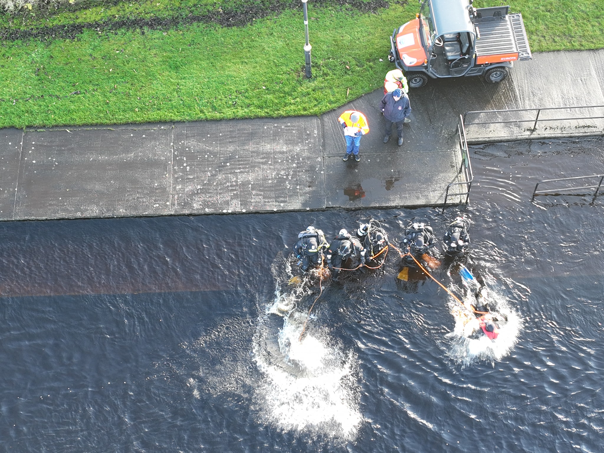 Divers entering the water beside a slipway